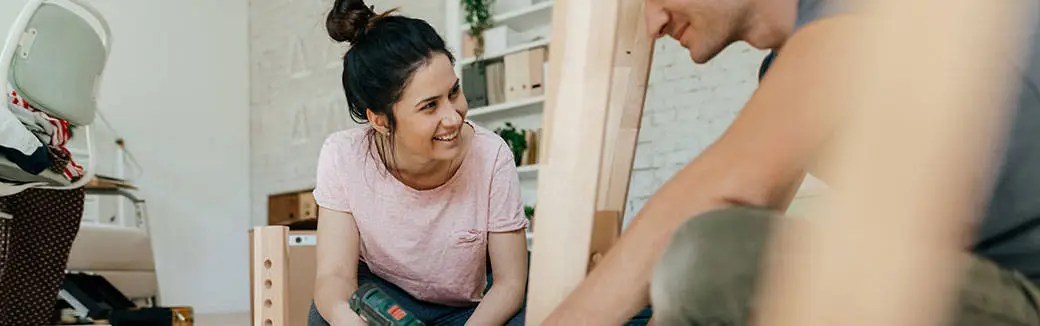 Smiling married couple sitting closely together, enjoying a warm moment working on a project together.
