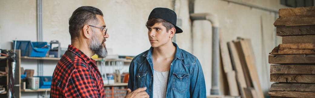 dad talking to teenage son in a garage