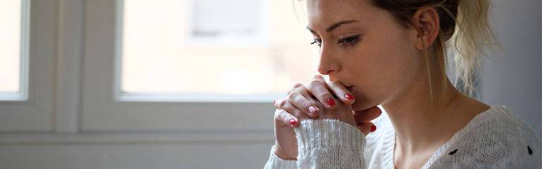 young woman praying with her head down.