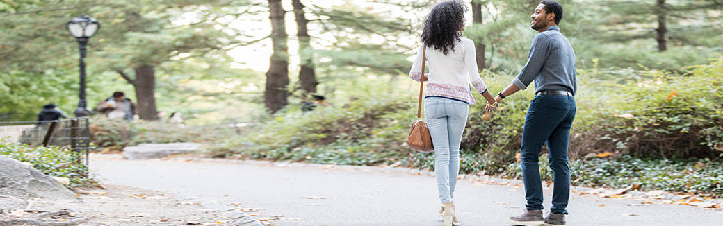man and woman walking hand-in-hand down a country road