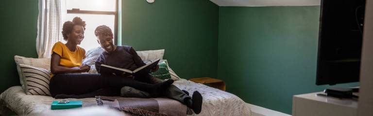 husband and wife sitting on bed looking at photo album